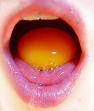 a raw egg held in a pretty mouth