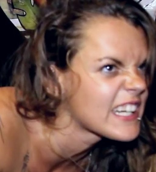 the facial expression of a woman getting an anal tattoo