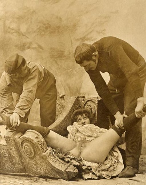 two men forcibly spreading a woman's legs