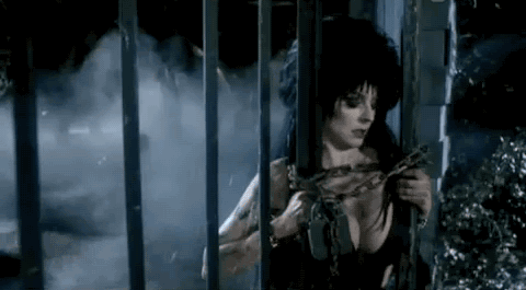 elvira breaks a chained gate with her magnificent breasts