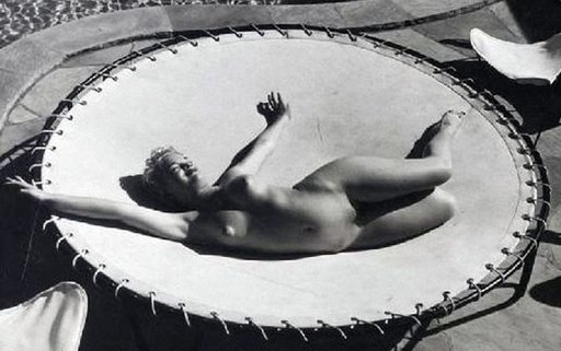 Marilyn Monroe naked on a trampoline beside a fancy swimming pool