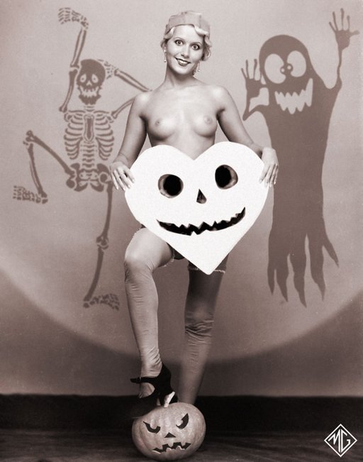 bare breasted nudie flapper burlesque dancer poses with one foot on a halloween pumpkin