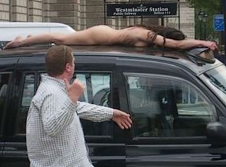 nude woman stretched out on the roof of a traditonal London black cab