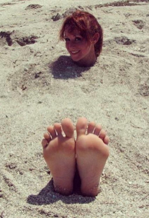 buried in the sand with her feet exposed and helpless to prevent tickling or a footjob