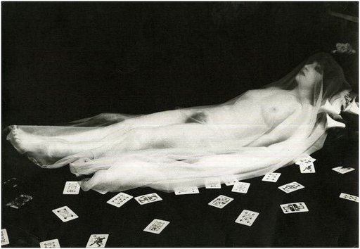 nude reclining under a transparent shroud surrounded by playing cards