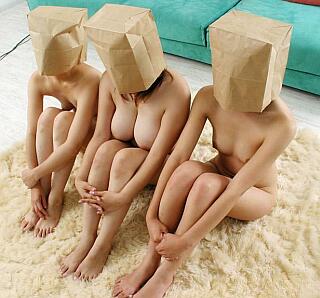 three lovely nudes on a sheepskin with brown bags over their faces