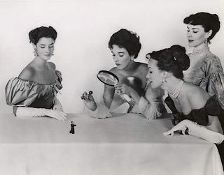 four fine but cruel ladies examine tiny man under a magnifying glass and attempt to pierce him with a hat pin