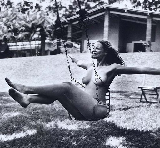 nudist naturist on a swing set with a big grin