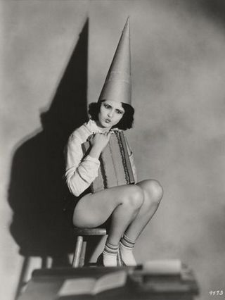 pretty girl wearing a dunce cap and looking puzzled