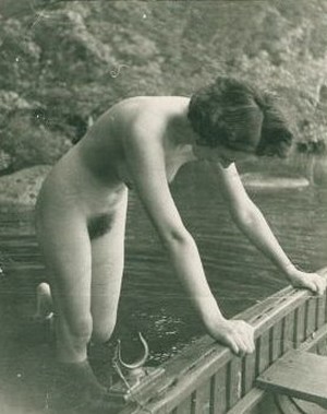 nude woman pushes boat out from shore