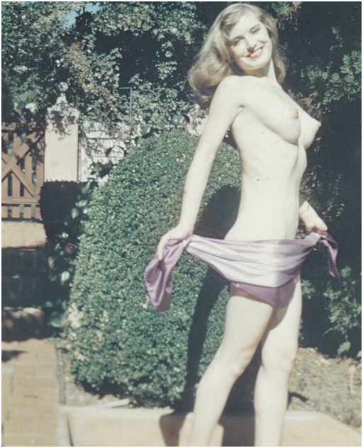 smiling vintage porn woman nude in a sunny fenced garden hides her pussy behind a classic striptease scarf