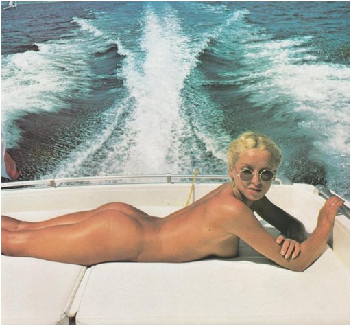 blonde model sunbathing naked on the rear deck of a power yacht