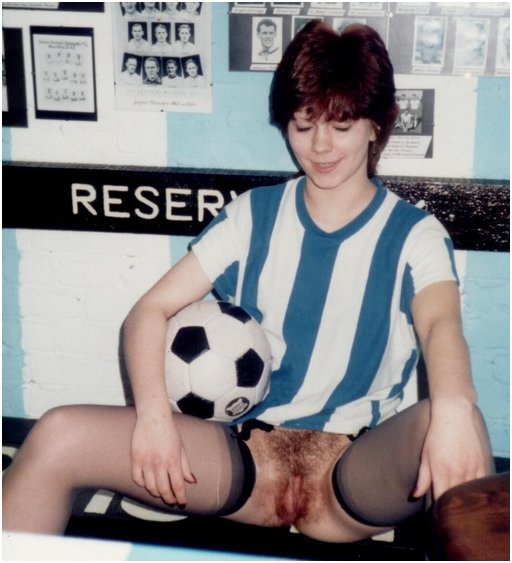 woman in soccer outfit with a football under her arm shows off her extremely furry pussy and general crotch area -- so much pubic hair!