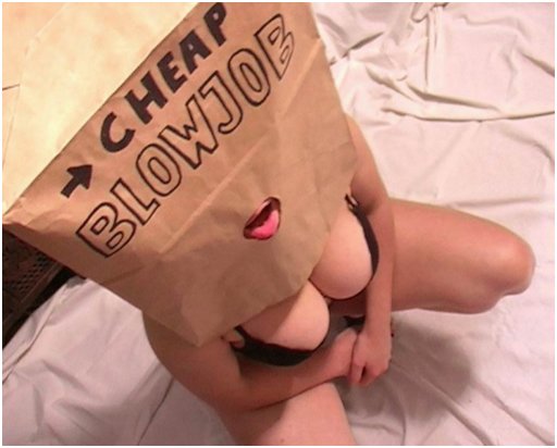 large-breasted woman is kneeling with a brown paper bag over her head, with only a mouth hole cut into it, and the bag is marked with a sign that says cheap blowjob
