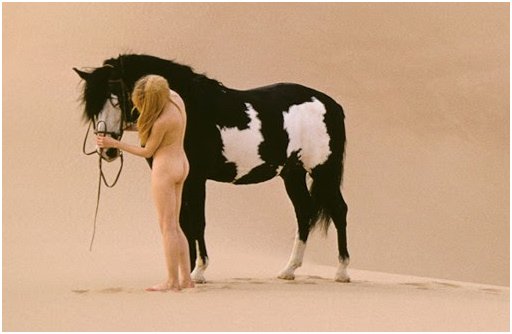 naked woman leading her horse over the hot desert sands