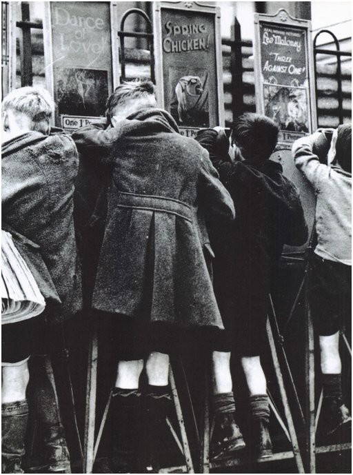 four men in schoolboy short pants watching mutoscope peep shows