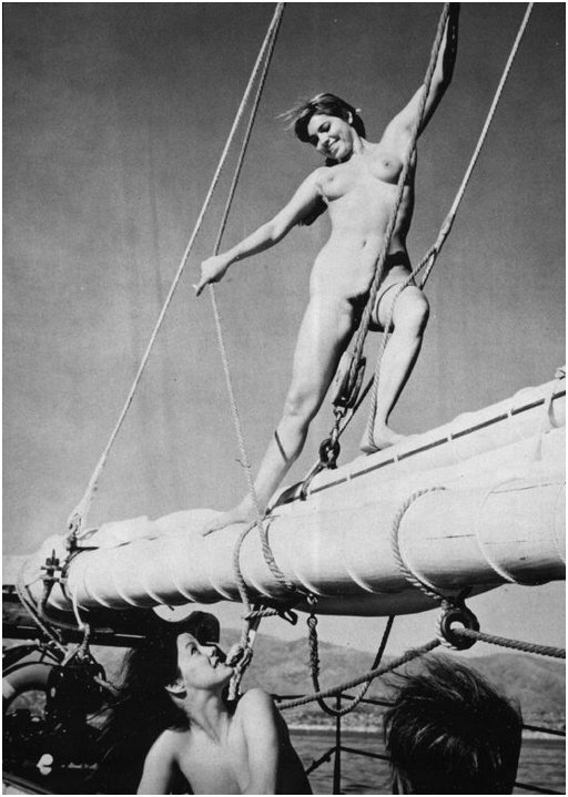 nude woman balanced dramatically in the rigging of a large sailing ship while another nude below on the deck smiles up at her