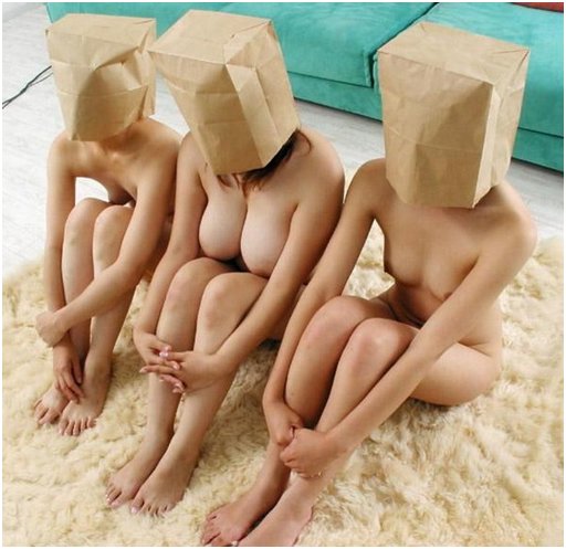 three lovely nudes on a sheepskin with brown bags over their faces